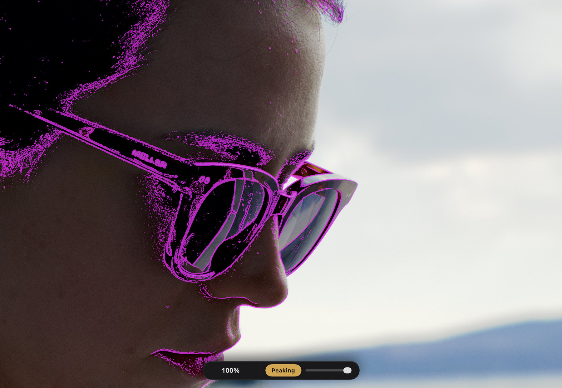 A profile portrait at 100% in the Focus Check window, with focus peaking painting the glasses, lashes and lip in magenta.